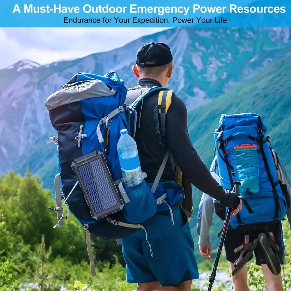 Black and gray solar power bank 20000mah rugged portable charger with a grid-like panel design attached to the side of a blue hiking backpack.