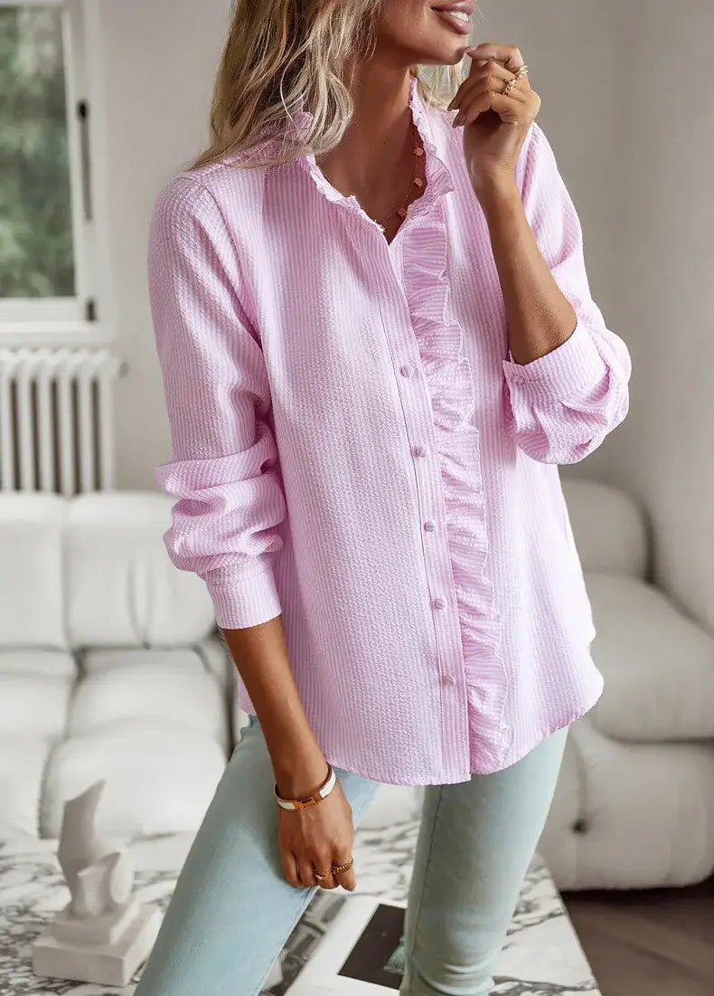 Blusa abotonada de manga larga color rosa suave con tejido de textura sutil y un delicado ribete con volantes a lo largo del canesú delantero.