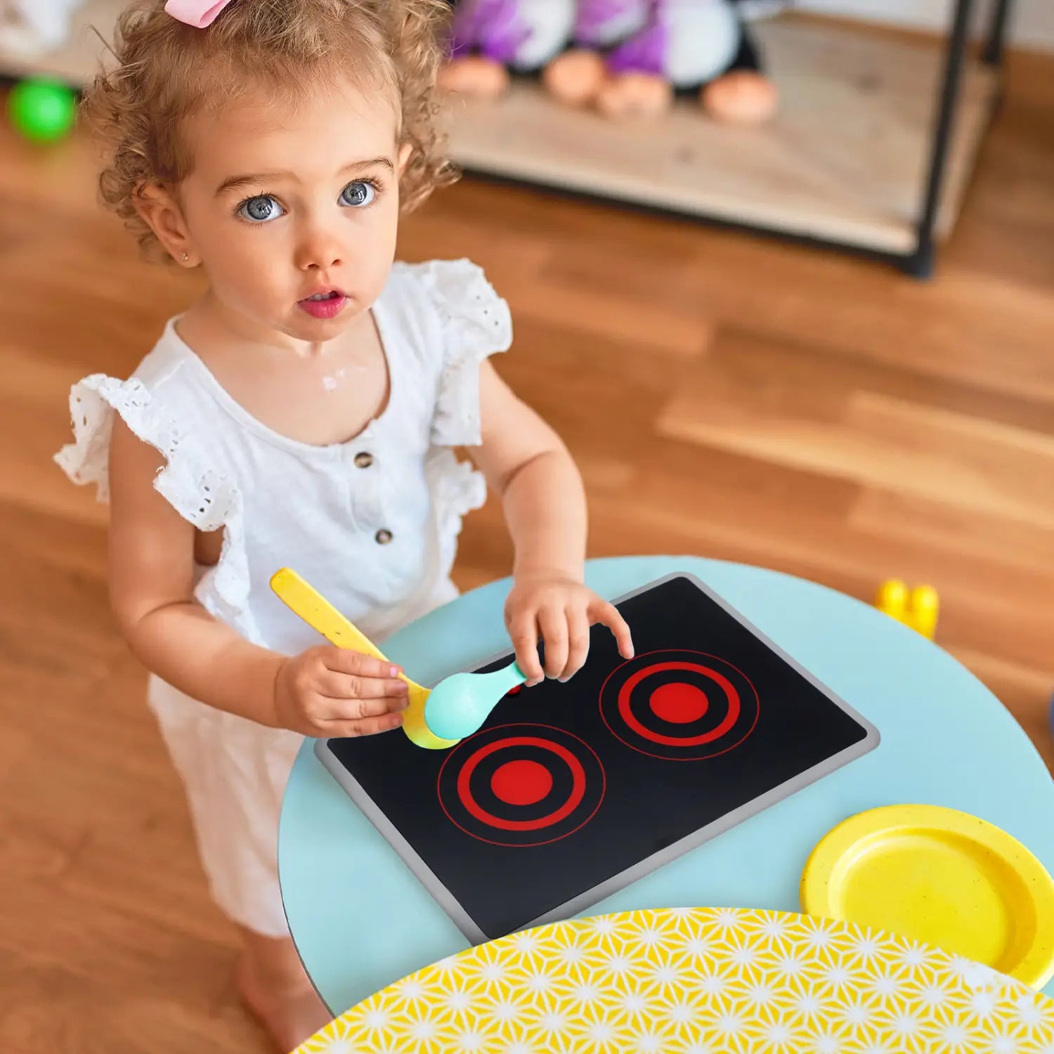 Schwarze Kinder spielen mit einem Induktionsherd-Spielzeug mit roten runden Kochfeldern, grauen Kanten sowie Sound- und Lichtfunktionen.