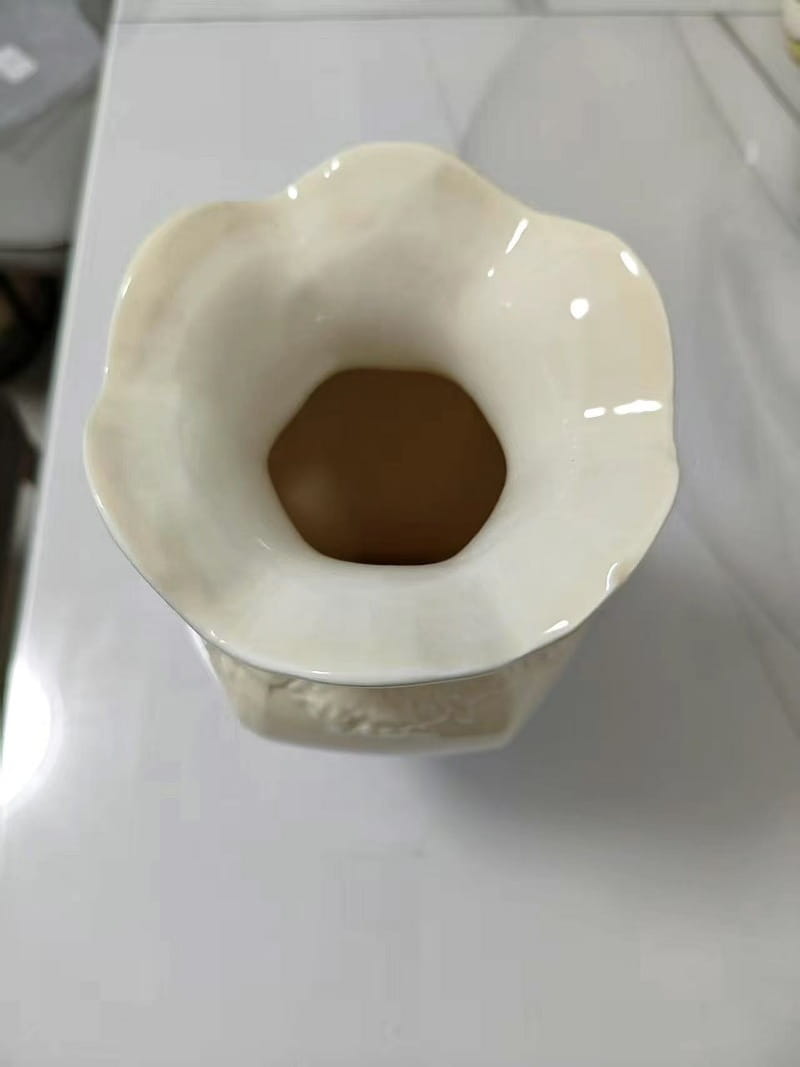 Jarrón de cerámica moderno francés color crema con un borde tipo flor acanalada y detalles discretos en relieve en su base, ideal para la decoración del hogar.