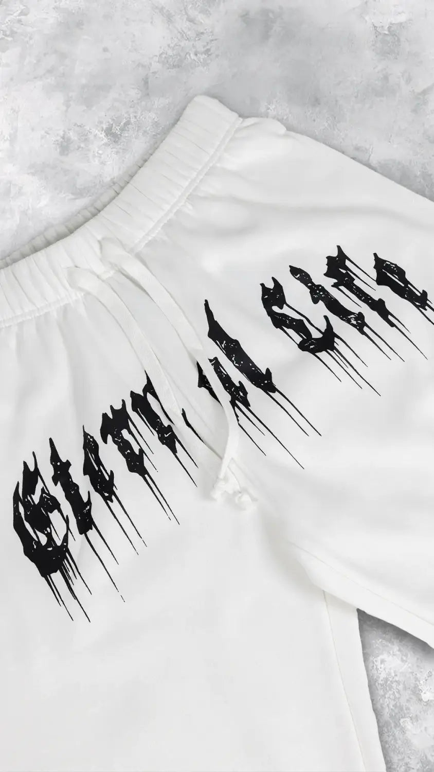 Pantalons d’entraînement graphiques pour hommes, sweatpants en blanc, avec des lettres de style fantôme noir qui s’écoulent sur la cuisse, adaptées aux vêtements d’entraînement.