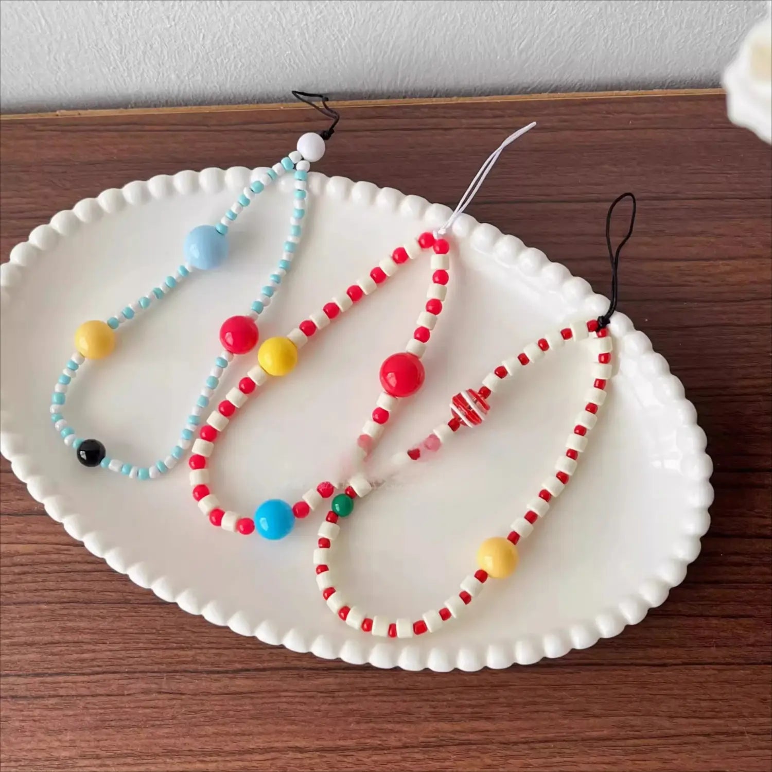 bracelet de téléphone à perles colorées comprenant des perles rouges, blanches, bleues, jaunes et vertes disposées selon un motif.