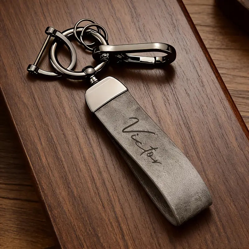 Silver-toned leather keychain with a brushed metal top and custom engraved victor script personalized gift.