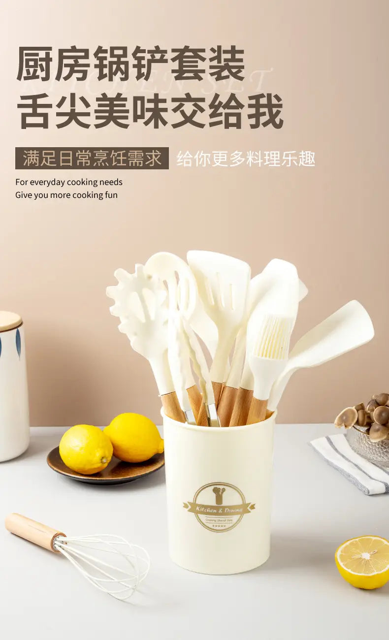 Cream-colored ceramic utensil holder with gold emblem containing a white silicone kitchen utensils set with wooden handles.