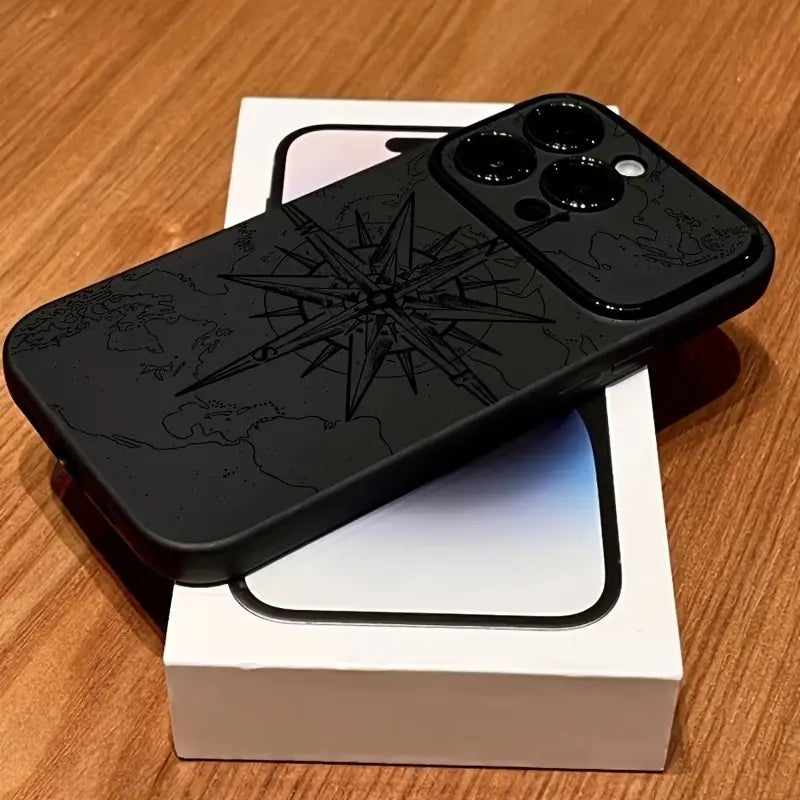 El reverso de una funda para iPhone negra mate a prueba de golpes que presenta un diseño de brújula grabada detallada y un patrón de mapa mundial.