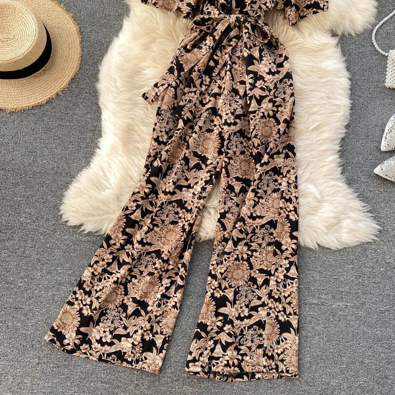 Pantalón de pierna ancha con estampado floral negro y beige con cintura atada como parte de un enterizo de pierna ancha floral con escote tipo bardot