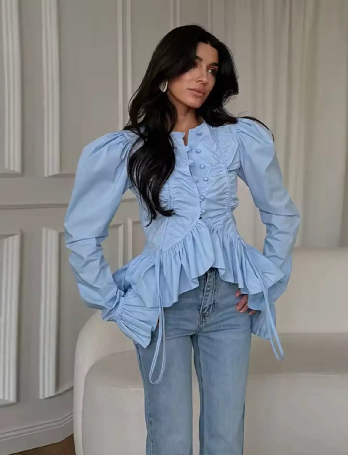 Light blue slim-fit design women long sleeve top with round neckline, puffed sleeves, ruffled peplum hem, and button detailing.