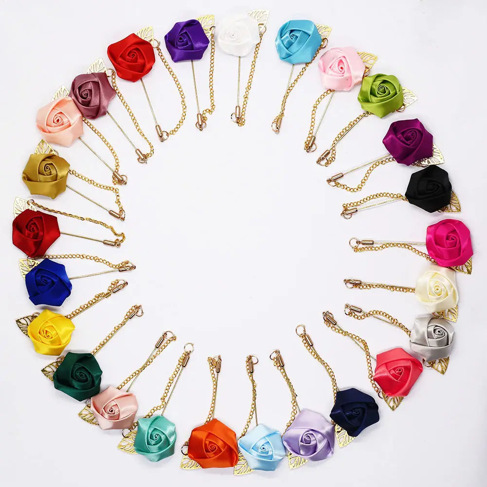 Un ensemble de broches en rose en satin de couleurs vives variées, avec des chaînes délicates à tons dorés et des accents feuillus, comprenant notamment une boutonnière de rose bordeaux avec chaîne dorée.