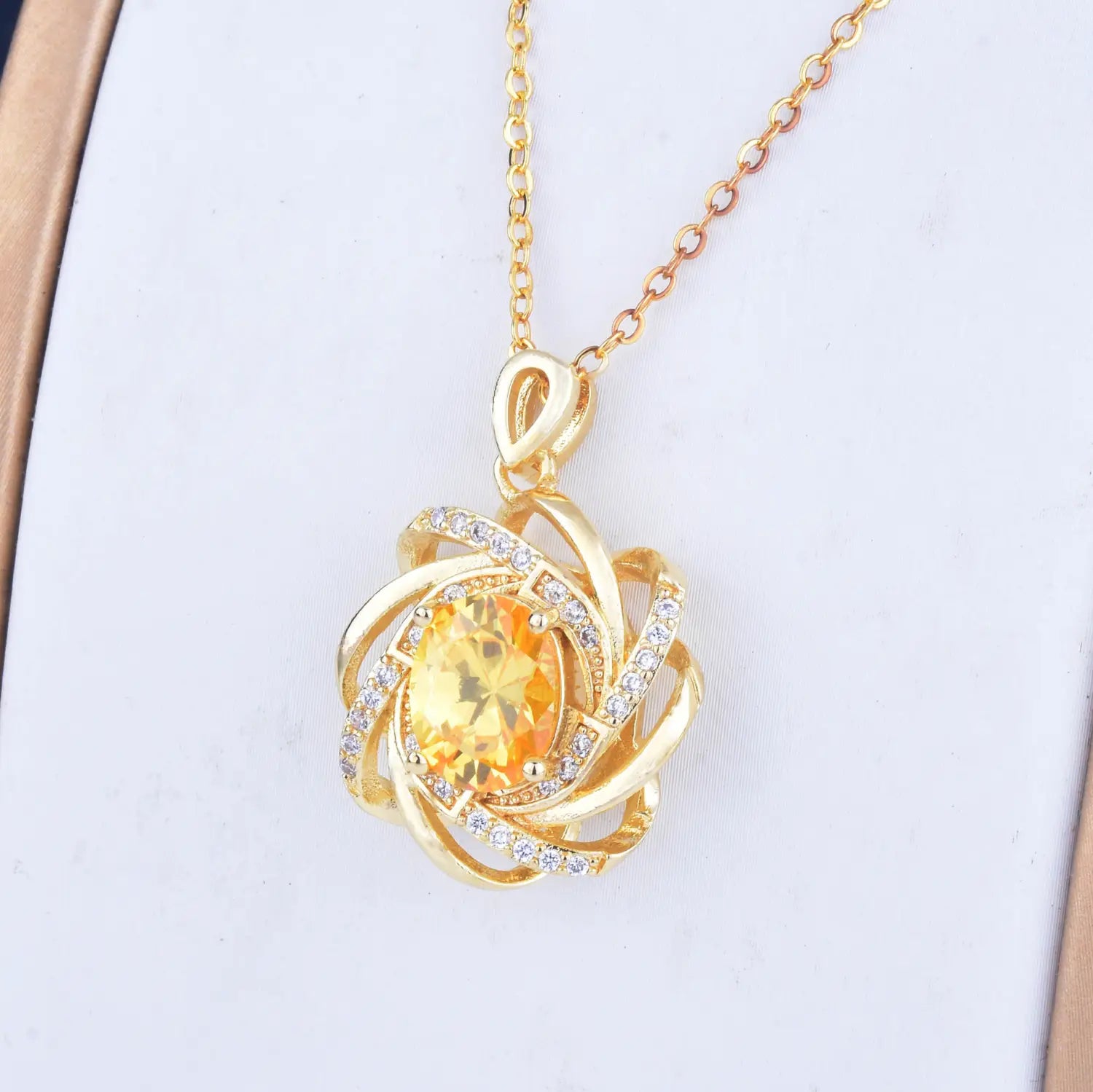 Collier pendentif moulin à vent en citrine doré comportant une pierre jaune centrale entourée de bandes dorées tourbillonnantes et de cristaux transparents
