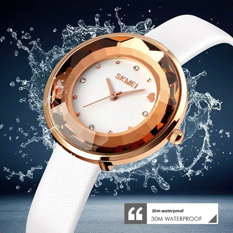 Floral quartz watch with a rose gold-toned case, white dial featuring diamond-like hour markers and a heart-shaped accent at the three o’clock position, a faceted bezel, and a smooth white leather strap in a gift box.