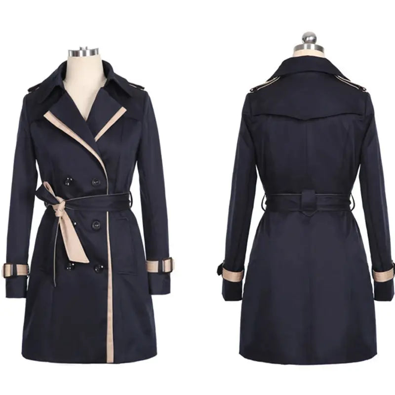 Navy blue women’s long trench coat with beige trim and belt featuring a double breasted design and windbreaker material.