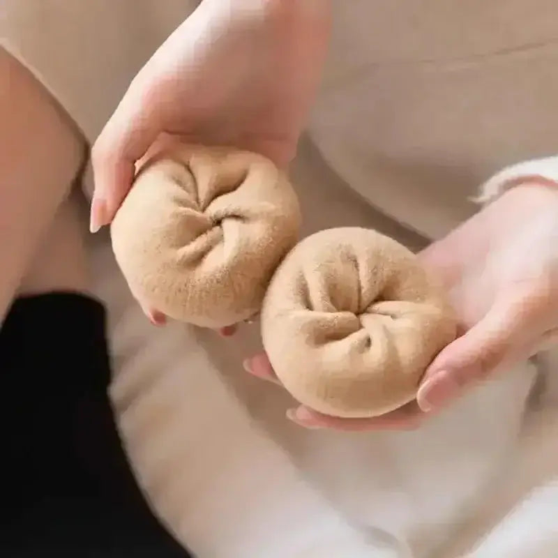 Two soft beige plush spherical winter thermal socks made of fleece lined cashmere wool with a textured surface and stitched top details.