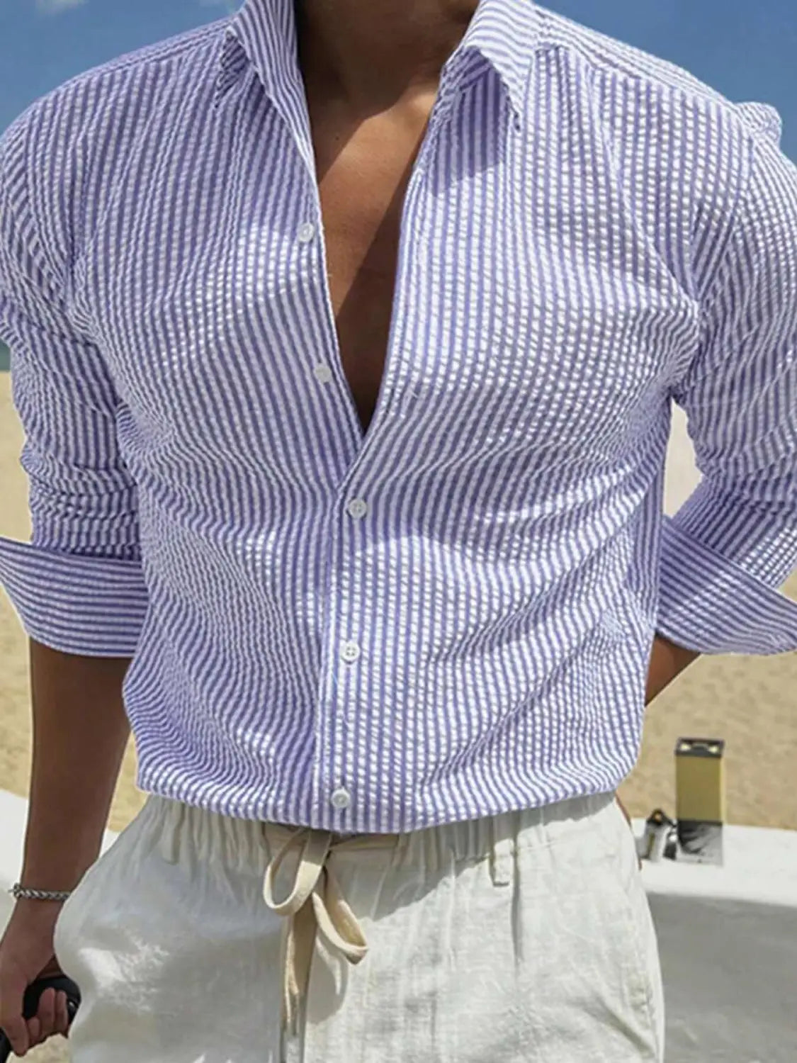 Chemise décontractée boutonnée manches longues à rayures verticales bleu clair et blanc pour homme, avec manches retroussées.