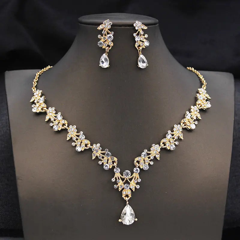 Un ensemble de collier floral aux tons dorés, avec des accents en cristal transparent et des pendentifs en forme de goutte provenant de la parure de couronne de mariée et de bijoux — accessoires de mariage en cristal.