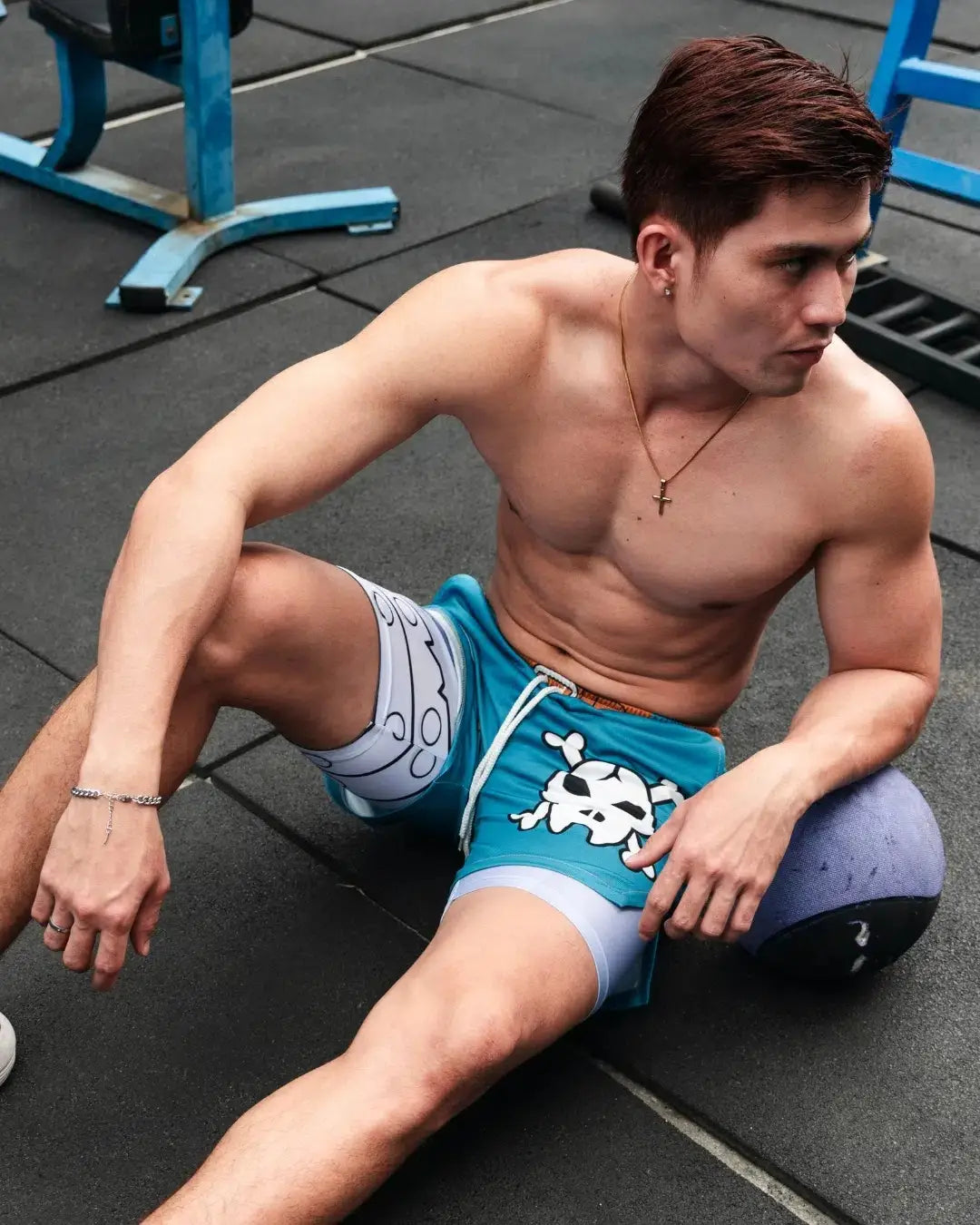 pantalones cortos de gimnasia azules con diseño de calavera y tibias cruzadas en blanco, usados sobre pantalones cortos de compresión color gris claro con marca Digimon Bandai Weregarurumon.