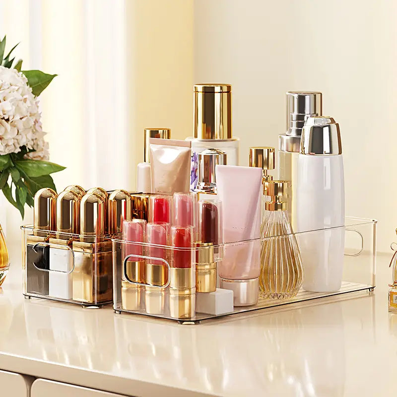 Bac de rangement pour réfrigérateur en plastique transparent avec poignées, en acrylique transparent, présentant des accents dorés et argentés, pour contenir divers produits de beauté.
