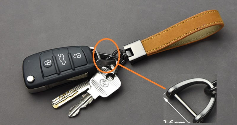 Black audi key fob with tan leather strap and silver metal ring attachment from a leather keychains set with multicolor metal clasp.