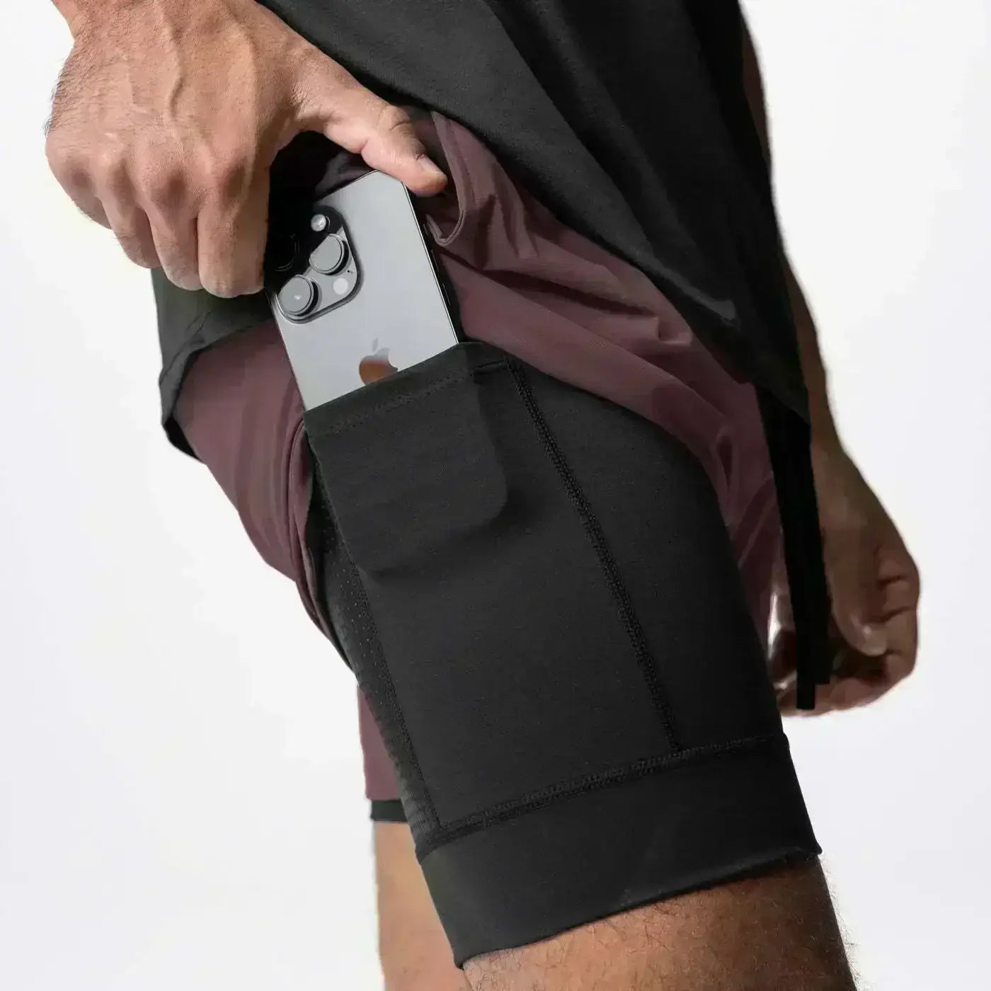 Pantalones cortos atléticos negros 2 en 1 para gimnasio de hombres con bolsillo para teléfono integrado, trabilla para la toalla y cintura elástica, diseñados para uso en entrenamientos.