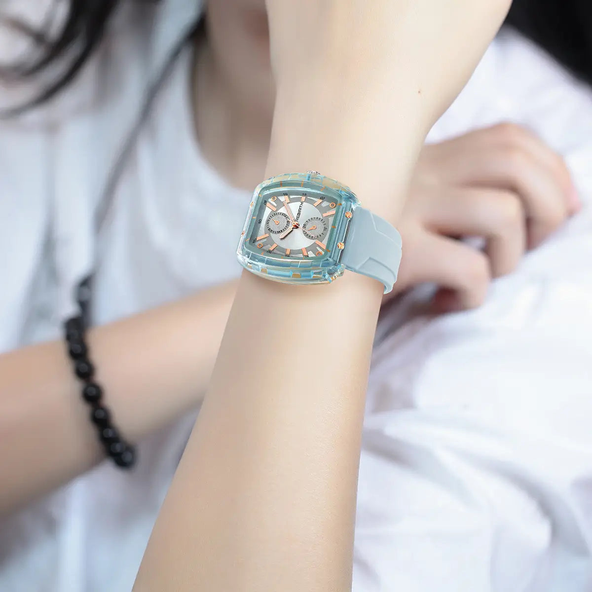 A translucent light blue silicone casual watch with a rectangular rose gold dial and matching strap worn on a wrist.