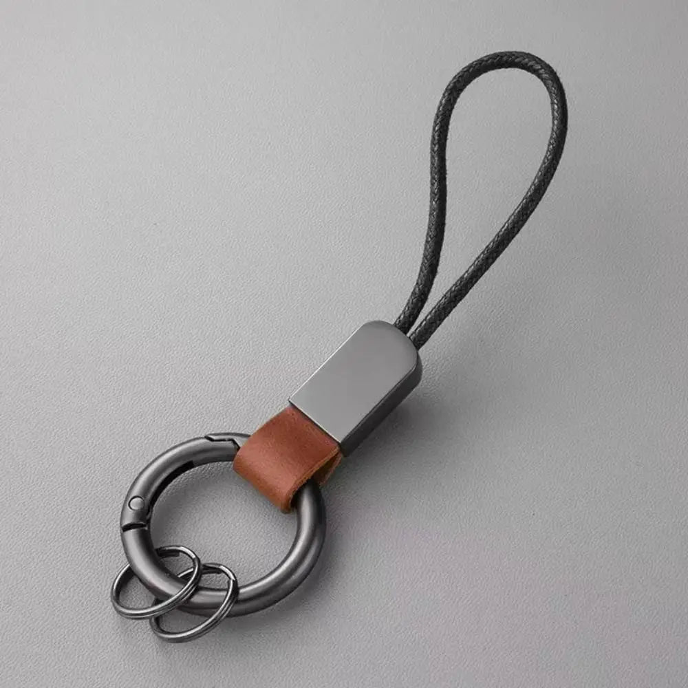 A leather carabiner keychain multifunctional key holder featuring a sleek matte-finished metal body with a brown leather strap and black braided cord.