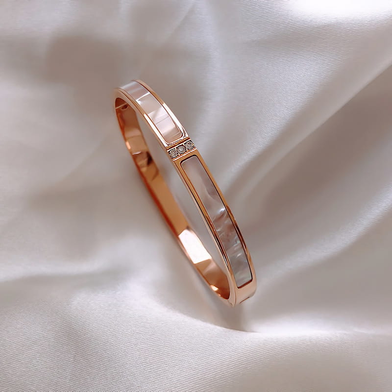 Armreif aus rostfreiem Stahl in Roségoldoptik mit Kristallen, mit modernem, schlankem rechteckigem Design, mit Einlagen aus Perlmutt und einer Reihe winziger Diamanten entlang der Mitte.