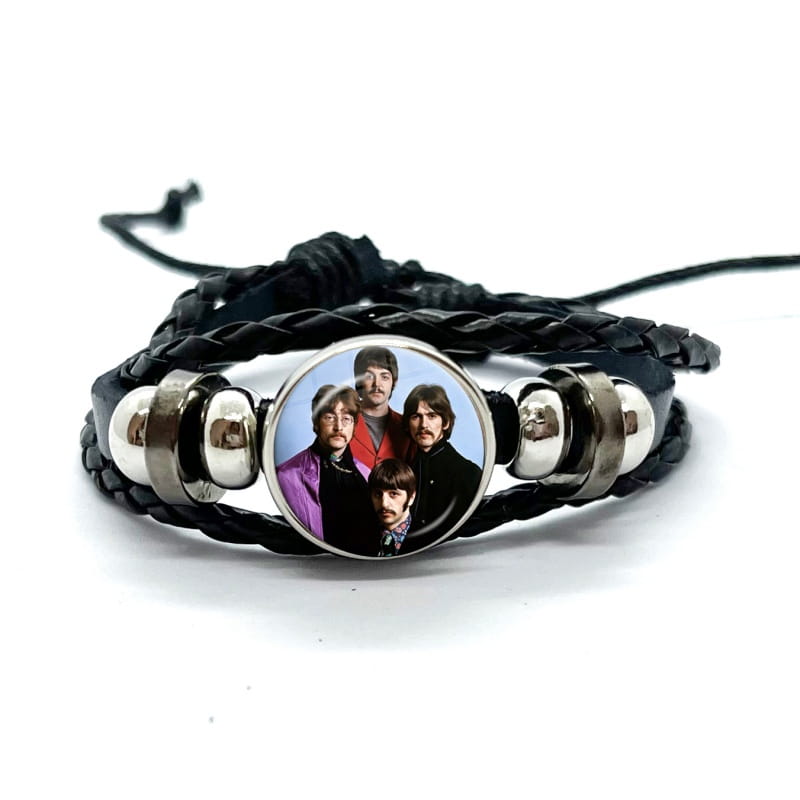 Black braided leather bracelet with a silver-toned circular charm featuring the Beatles logo in glass dome jewelry style.