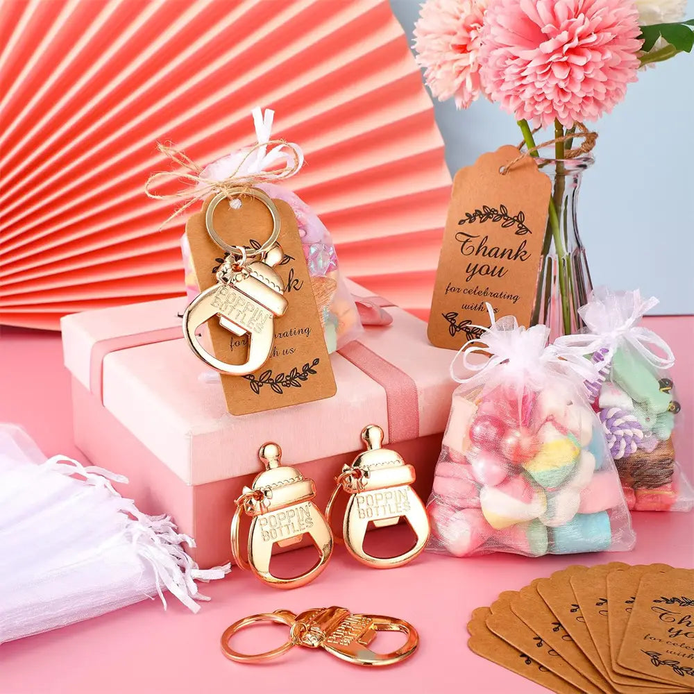 Gold-colored metal bottle opener keychains with a baby bottle design and engraved text for baby shower bottle opener favors set.