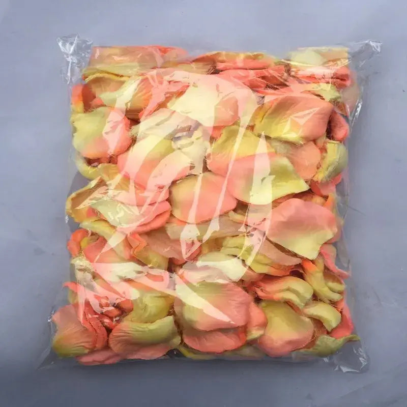 A clear plastic bag filled with artificial peach and yellow gradient rose petals for wedding decor from the 5500 colorful rose petals collection.