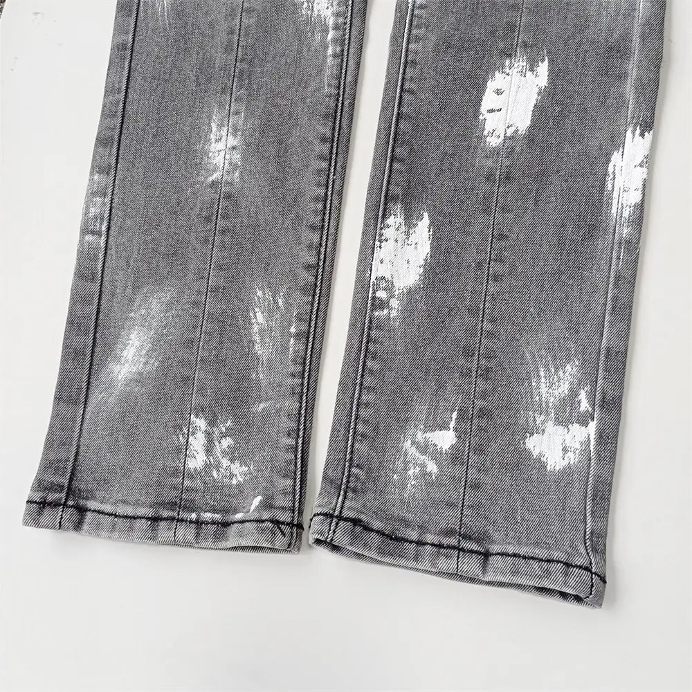 Jeans skinny déchirés pour hommes en denim gris délavé, avec effets d’éclaboussures de peinture blanche et détails en bleu de délavage rétro vintage.