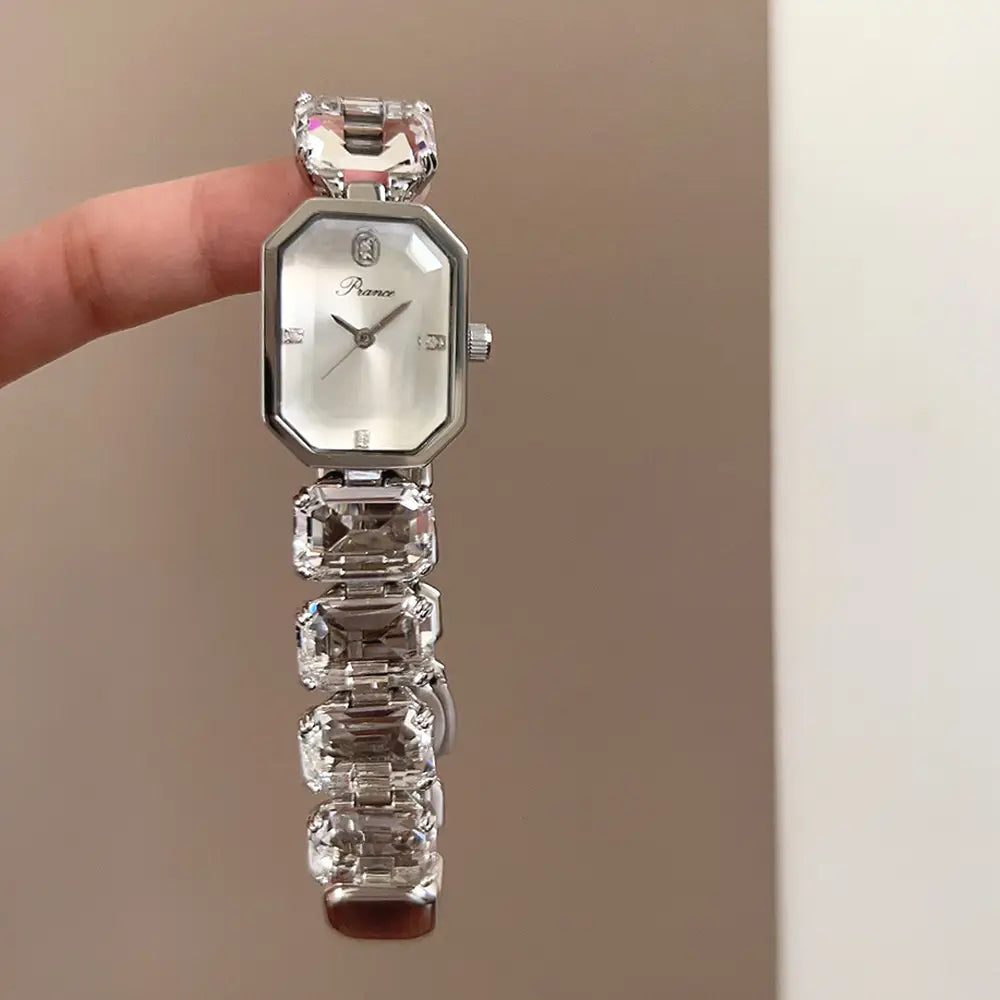 A sleek silver-toned women quartz crystal watch with an octagonal face and a bracelet adorned with large faceted clear crystals.