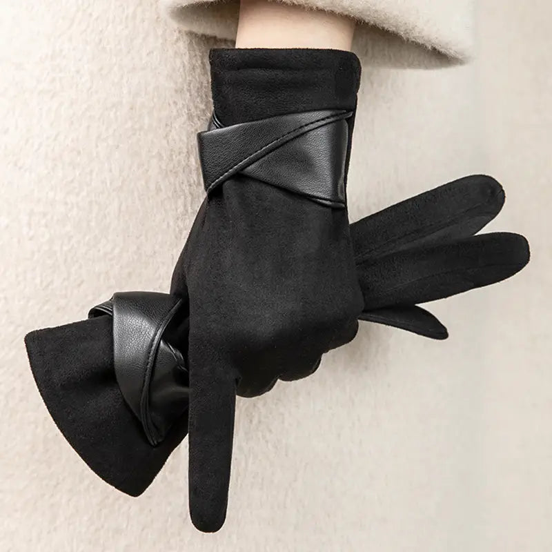Guantes de invierno para mujer con pantalla táctil en negro, con textura tipo ante y correas de cuero lisas que forman un patrón en X en el lado posterior de la muñeca, con detalle de lazo de terciopelo