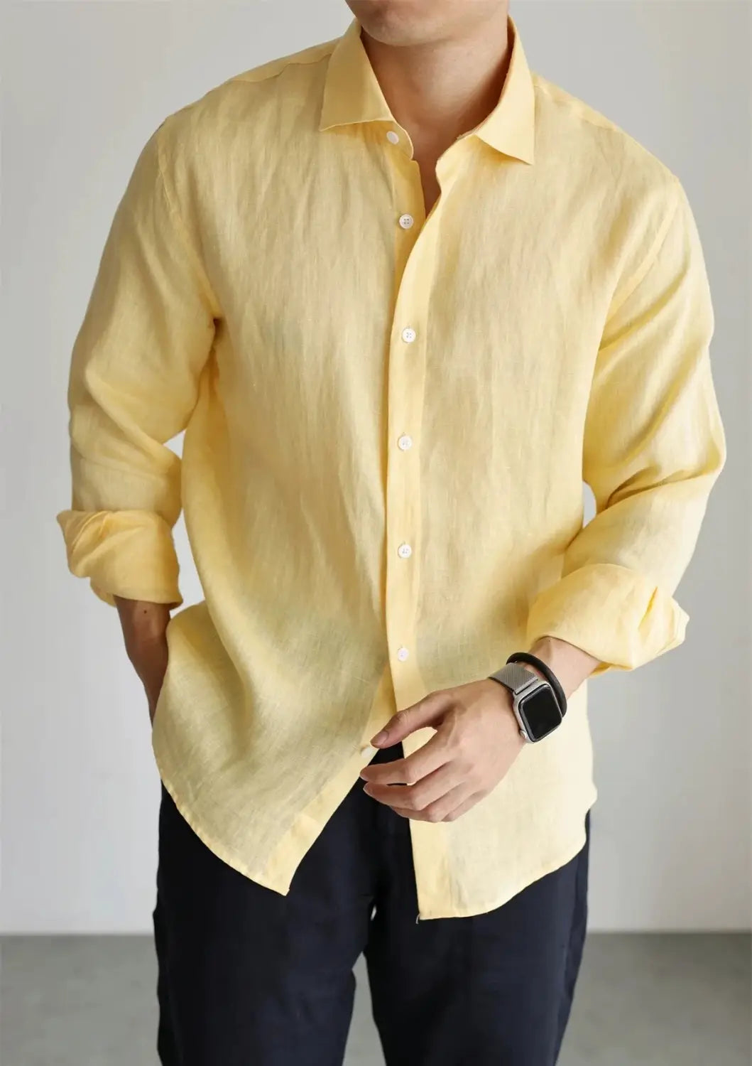 A pale yellow men cotton linen casual button down shirt made of lightweight linen fabric with long sleeves and rolled cuffs.