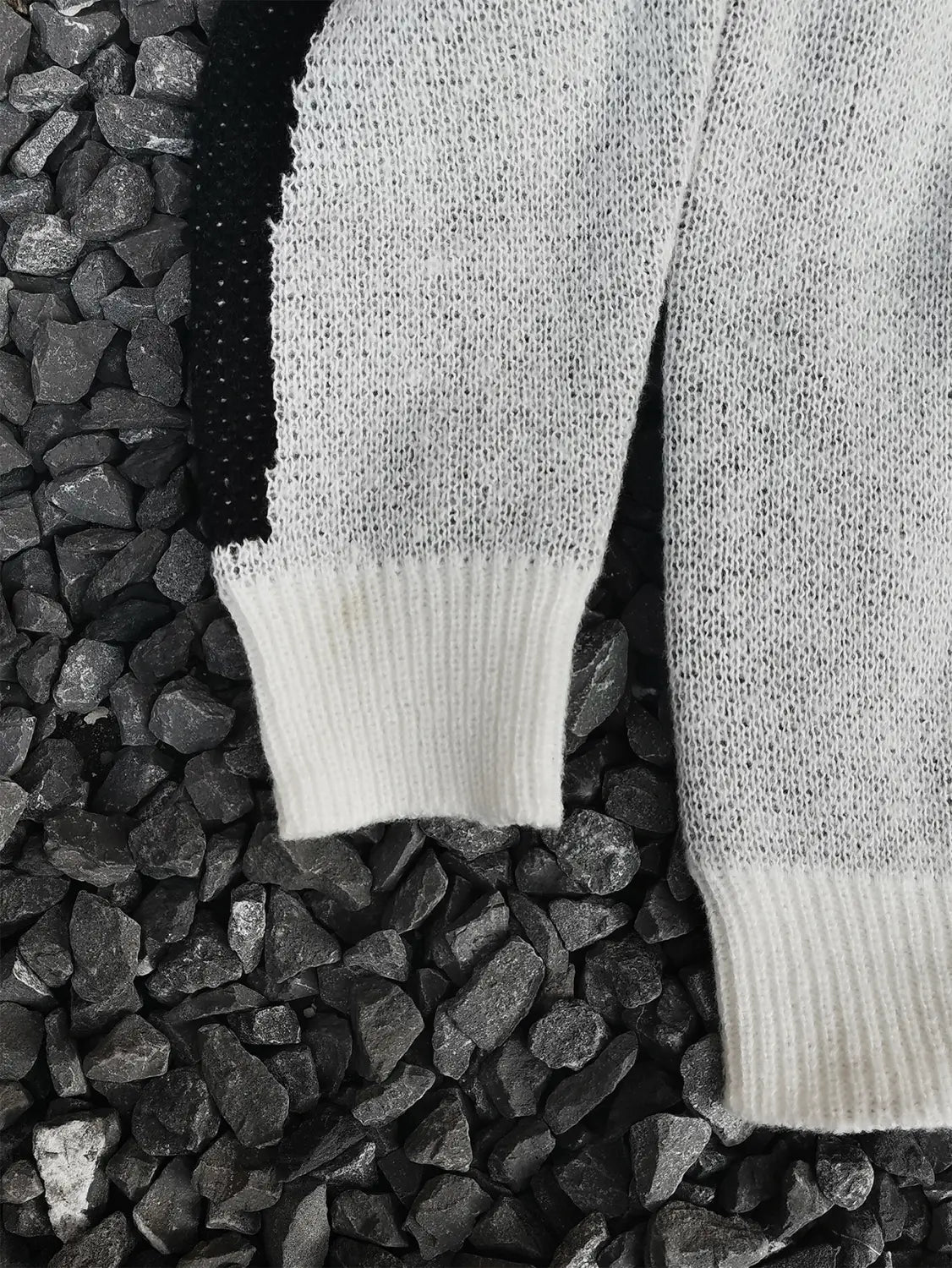 Pull gothique à jacquard squelette en maille gris clair doux pour hommes, présentant un poignet blanc côtelé et un panneau noir contrastant le long de la manche.