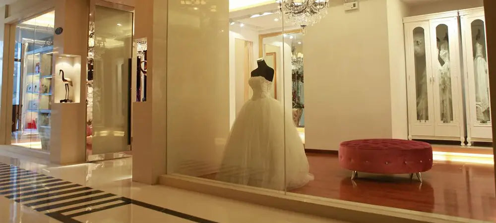 Ein weißes maßgeschneidertes trägerloses A-Linien-Hochzeitskleid aus Satin mit Bodenlänge, auf einem Bühnenschaufenster-Mannequin in einer eleganten Boutique präsentiert.