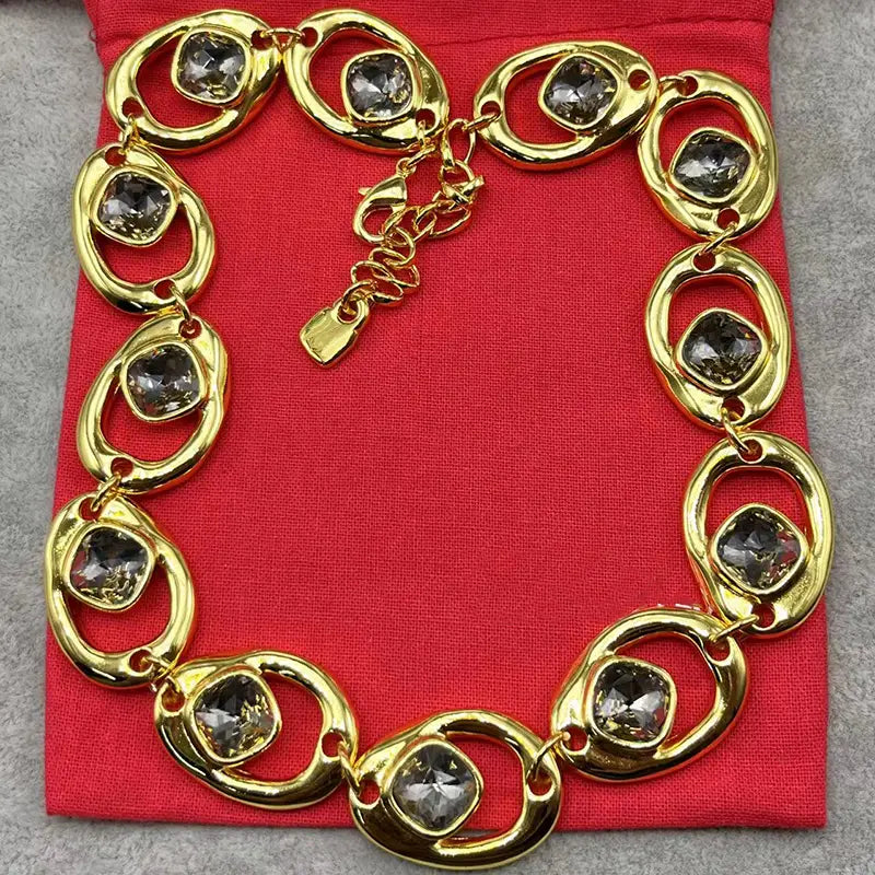 Gold-toned necklace from crystal pendant jewelry set gold and silver tone featuring bold oval-shaped links with embedded dark gray faceted stones.