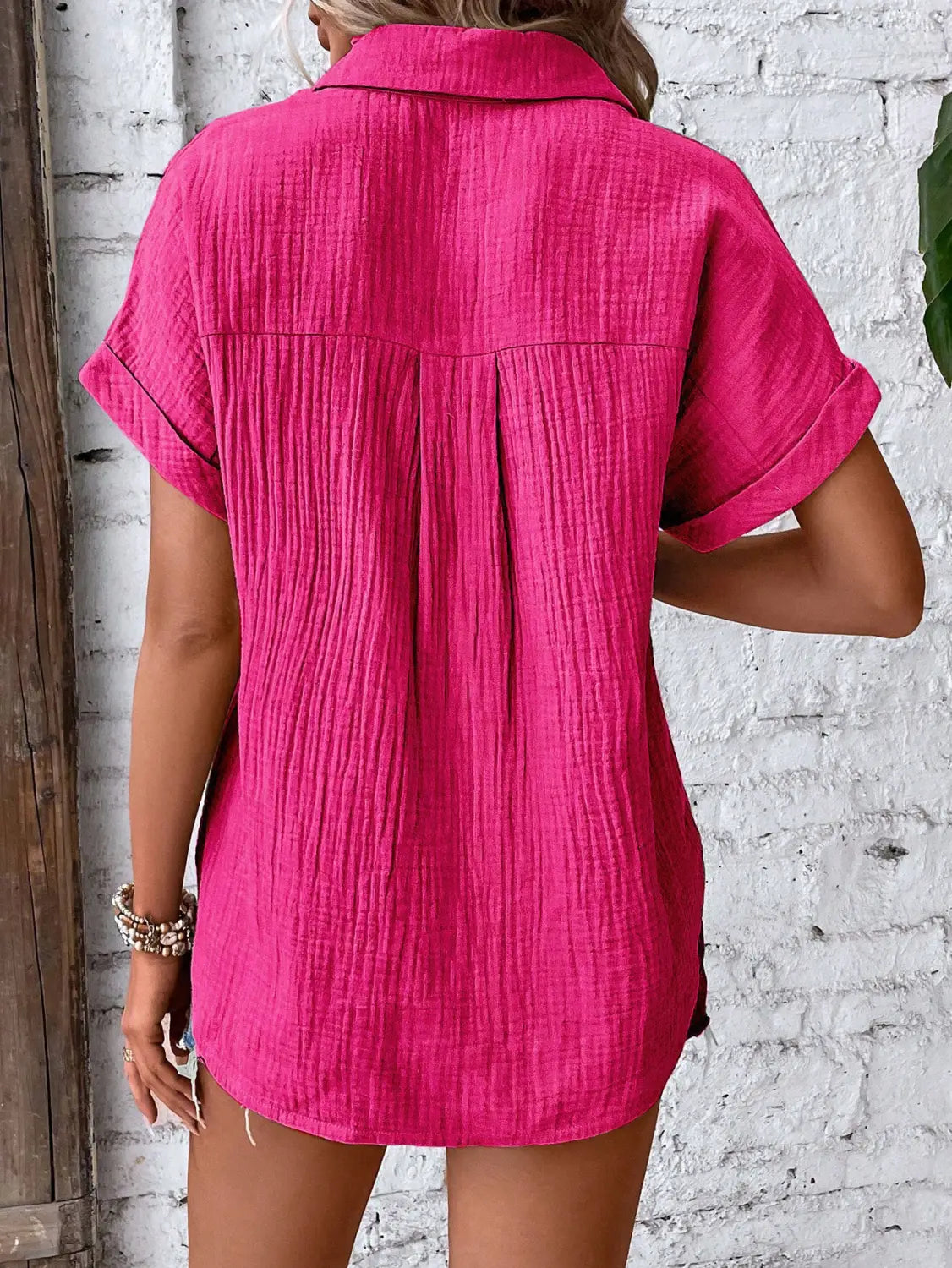 A vibrant fuchsia women cotton short sleeve button up shirt dress with textured crinkled fabric and rolled cuffs.