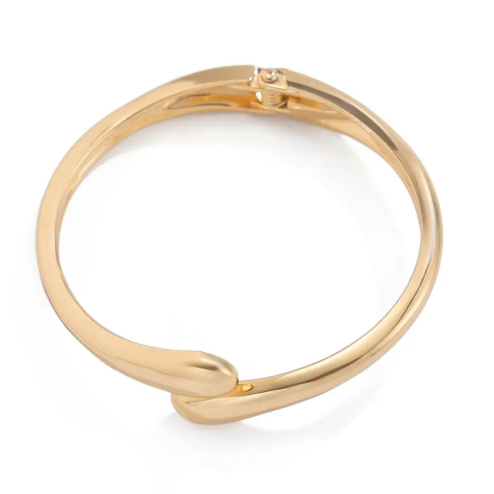 Wide metal bangle featuring a gold-toned curved design with a small clasp in a sleek chunky open cuff bracelet style.