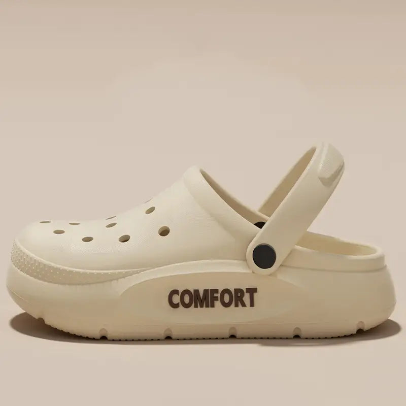 Cremefarbene Eva Slip-on Cushion Clog-Sandalen aus EVA-Material mit dicker, gepolsterter Sohle und dem Wort „comfort“ dunkelbraun geprägt an der Seite.
