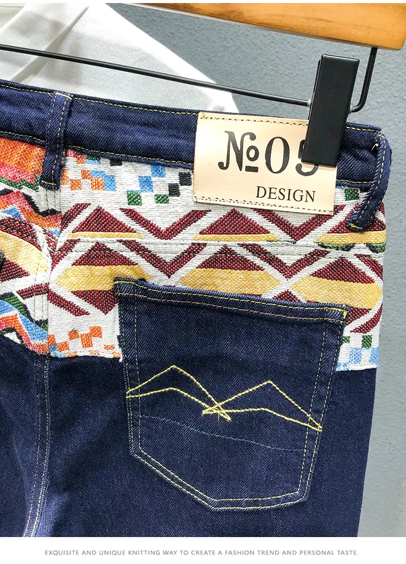 Men slim fit stretch embroidered white denim jeans featuring dark blue denim with a vibrant geometric patterned waistband of multicolored triangles and squares in orange yellow red green and white.