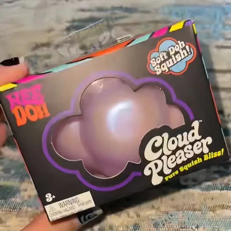 a lavender cloud-shaped soft doh squishy toy named cloud plexer in its original packaging for needoh cloud pleaser slow rising squishy toy.