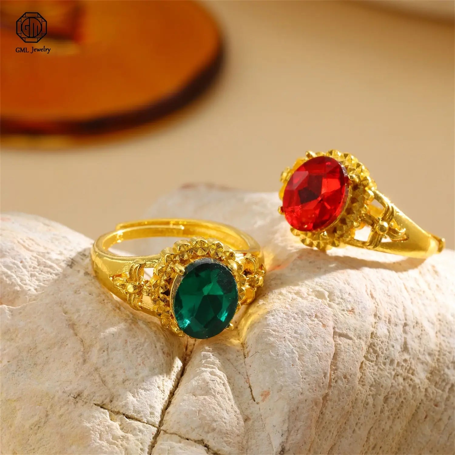 gold adjustable rings featuring ornate filigree detailing with oval-cut vibrant red and deep green gemstones in a fade resistant sand gold adjustable matte wide band design resting on a textured white surface