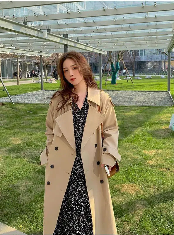 Beige women double breasted trench coat featuring black buttons and a classic tailored design.