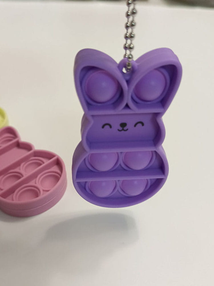 Purple rabbit pop it fidget keychain made of silicone with a silver chain for portable stress relief.