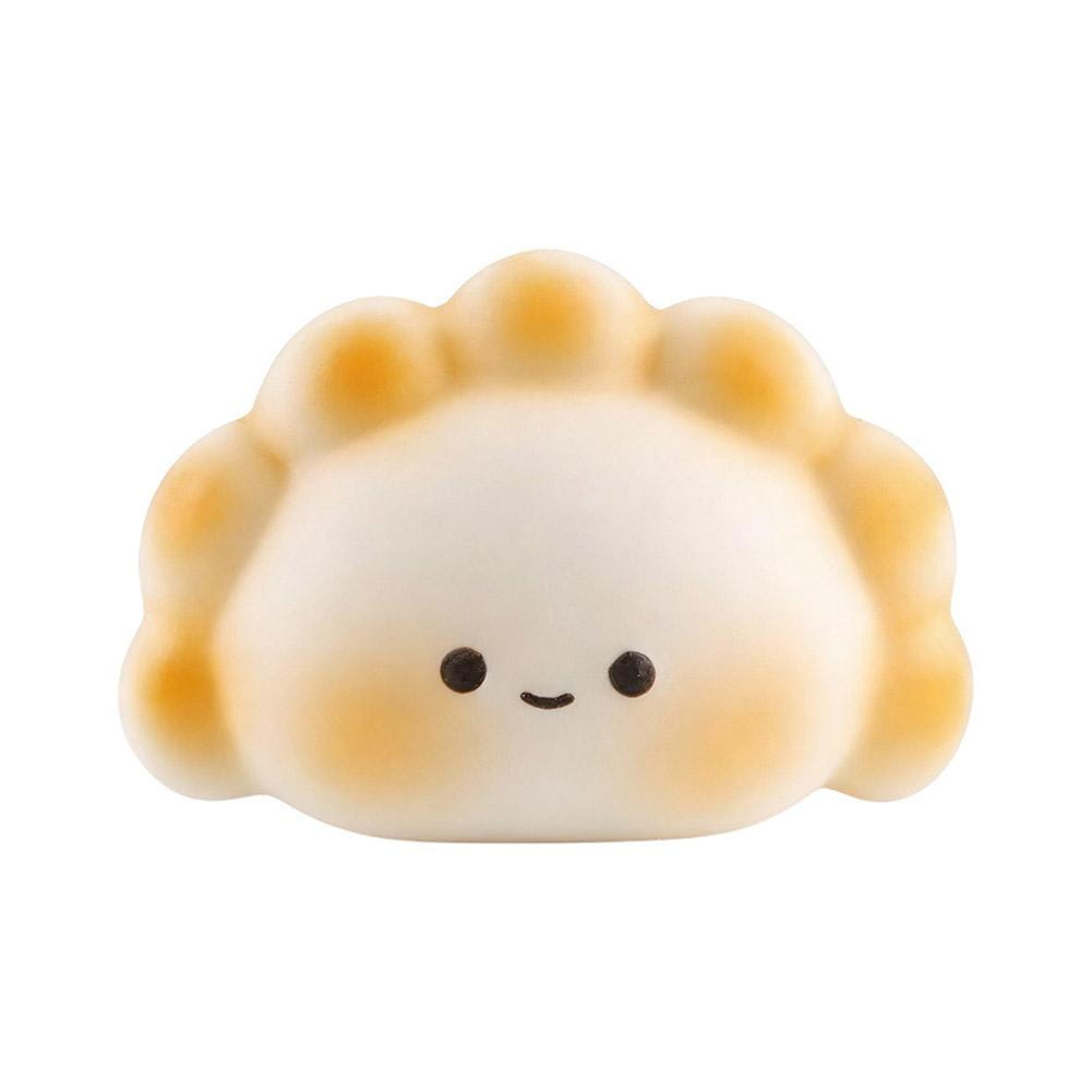 Lindo juguete exprimible para aliviar el estrés con forma de dimsum en color blanco y marrón dorado, con carita sonriente, diseñado para juguetear y aliviar la ansiedad.