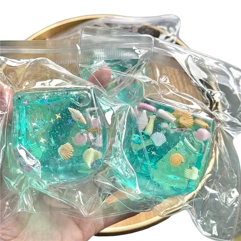 Teal translucent resin sea-themed squishy cube with embedded seashells and star glitter viewed from the front