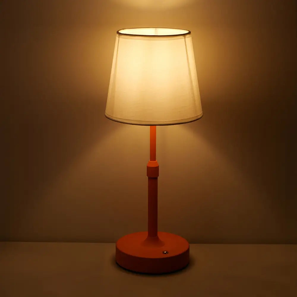 Vorderansicht einer warmtonigen orangefarbenen Touch-Tischlampe mit einem weichen cremefarbenen, plissierten Stoffschirm.