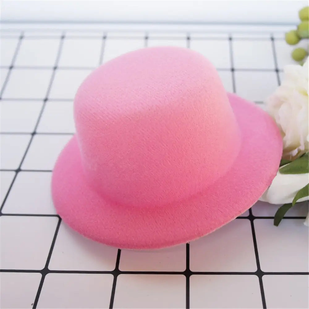 Un chapeau melon (bowler) en feutre rose tendre, à calotte arrondie et bord large, conçu comme accessoire de mode pour chapeau de poupée en peluche pour des poupées de 60 cm.