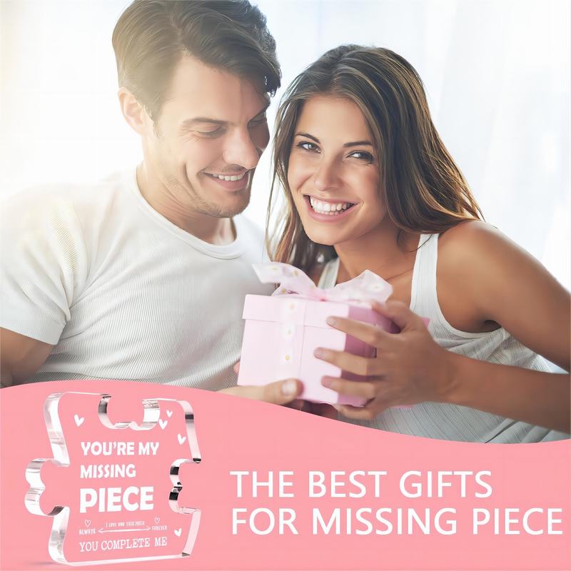 Une boîte cadeau rose avec un nœud assorti contenant un souvenir en acrylique représentant un couple de pièces de puzzle.
