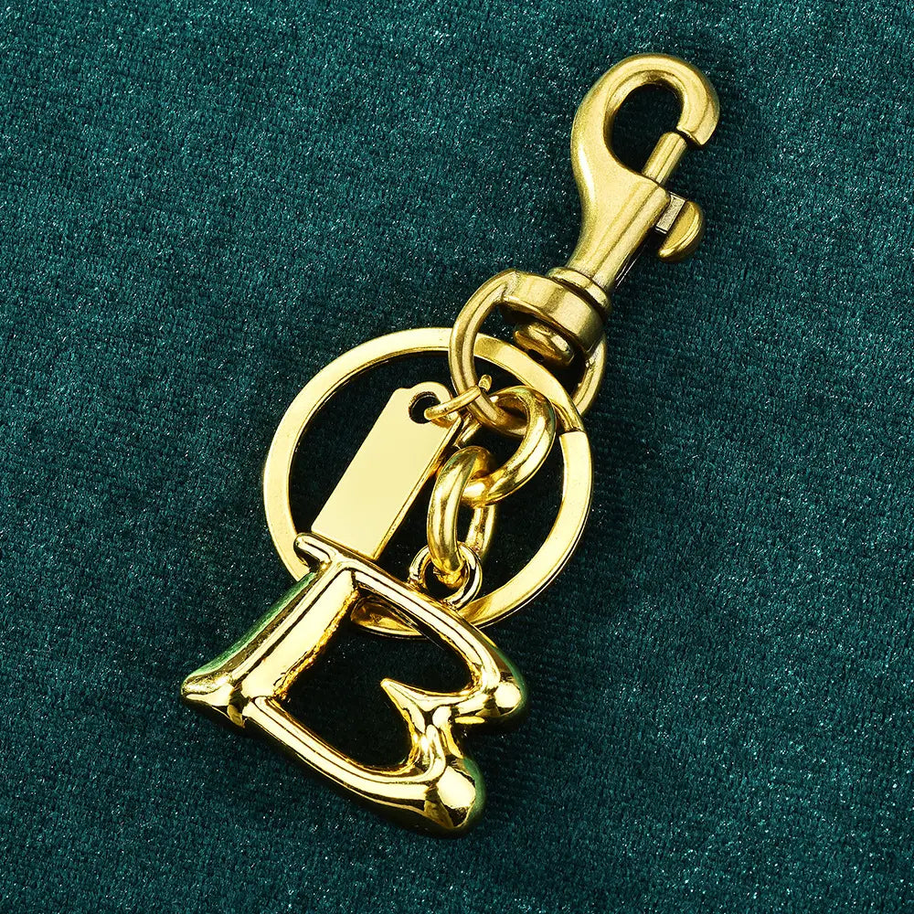 Gold-tone metal keychain with a prominent letter b charm, circular ring, and swivel hook designed as a car accessory.