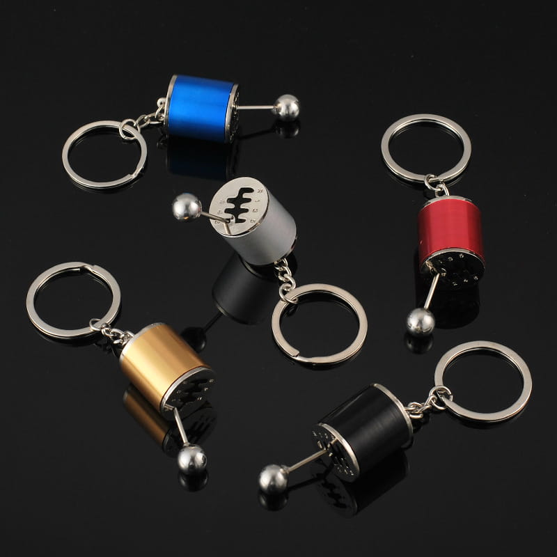 Set of colorful metallic manual gear shift car keychains in blue silver red gold and black finishes.